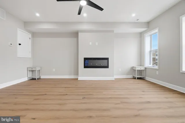 a view of an empty room with window and wooden floor