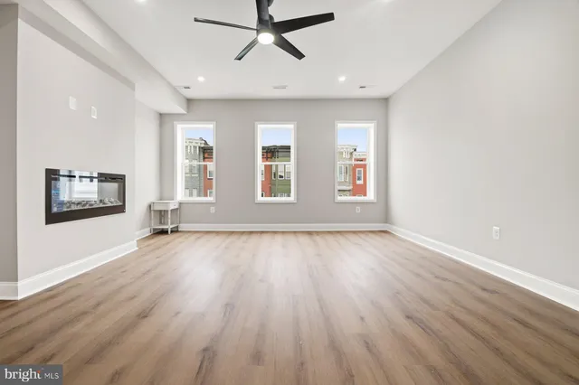an empty room with wooden floor and windows