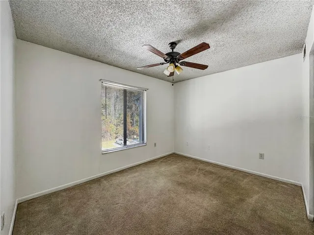 an empty room with windows and fan