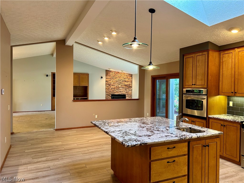 8763 Timber Edge Drive North Ridgeville, OH 44039 - Photo 6 of 40 Kitchen featuring tasteful backsplash, a kitchen island with sink, stainless steel oven, sink, and vaulted ceiling with skylight