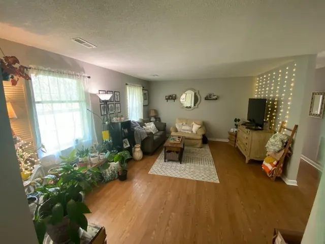 a living room with furniture floor to ceiling window and a flat screen tv