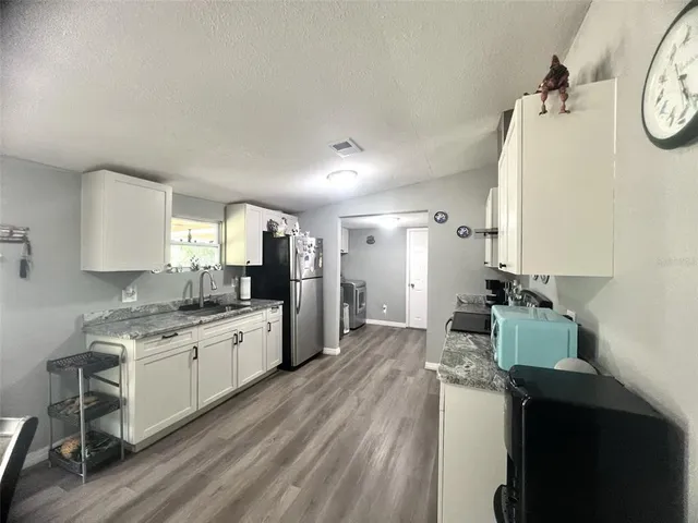 a kitchen with granite countertop a stove a sink and a refrigerator