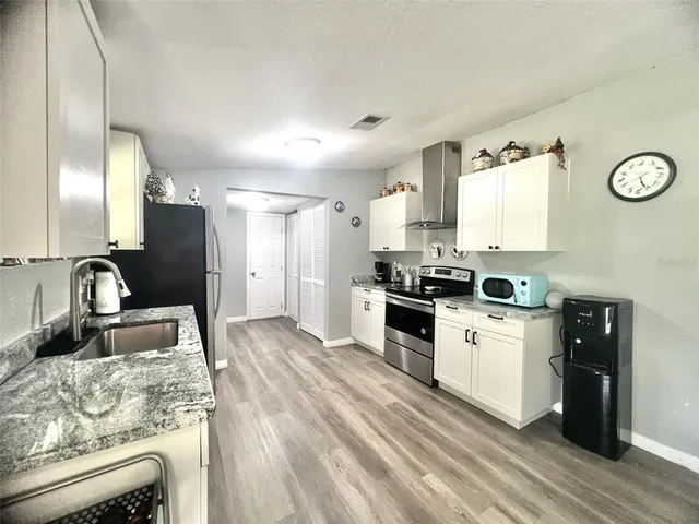 a kitchen with stainless steel appliances granite countertop a refrigerator a sink and a stove with wooden floors