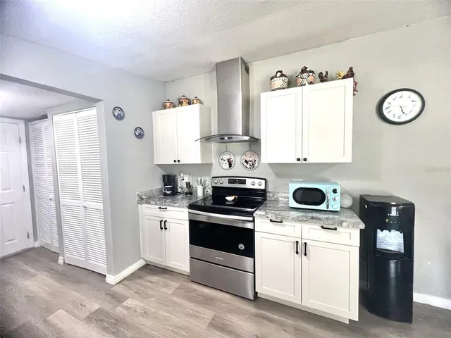 a kitchen with stainless steel appliances granite countertop a stove a sink and white cabinets