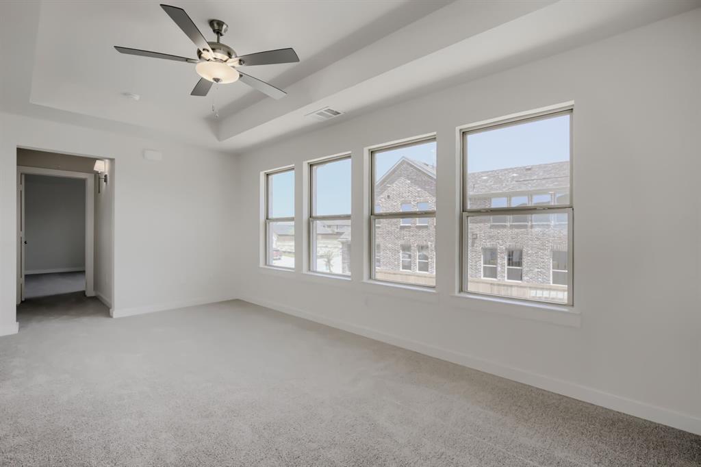 828 Stone Grv Road Lavon, TX 75166 - Photo 14 of 27 Spacious interior room featuring a tray ceiling, contemporary ceiling fan, light gray carpet, and a row of four windows