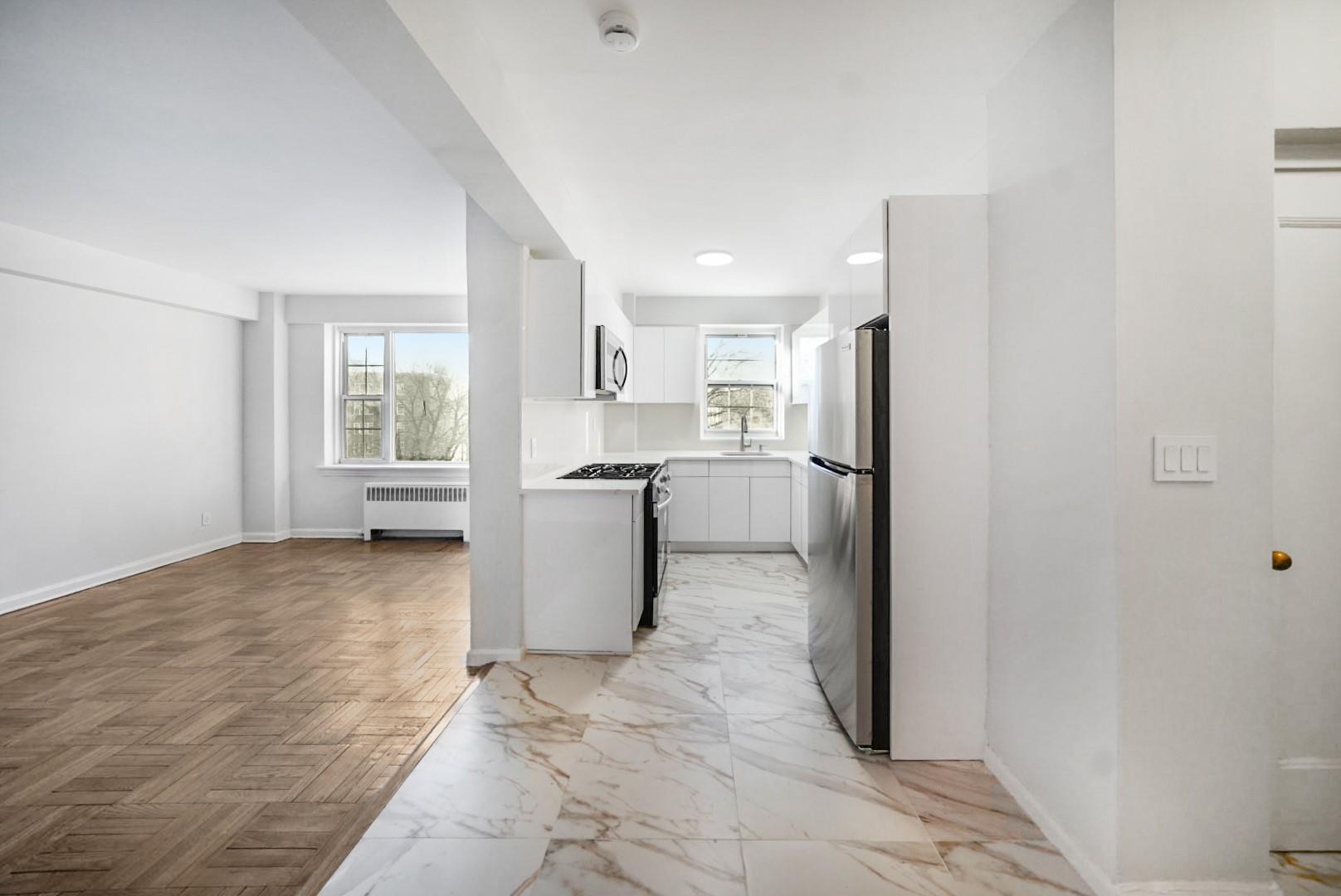 220 Pelham Road, Unit 5A New Rochelle, NY 10805 - Photo 1 of 1 Kitchen with light parquet floors, sink, radiator heating unit, white cabinetry, and stainless steel appliances