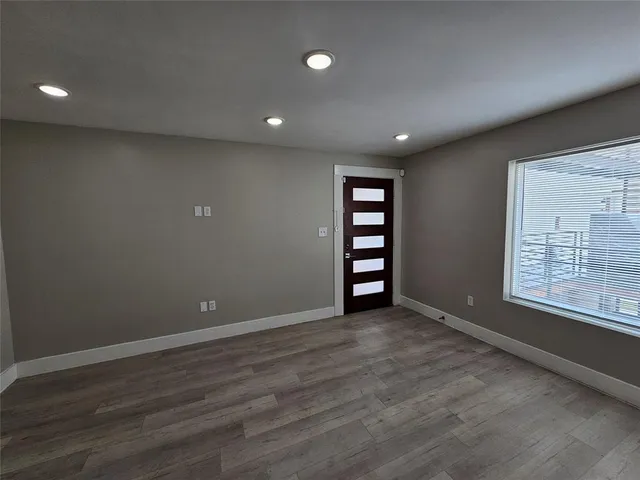 an empty room with wooden floor and entrance