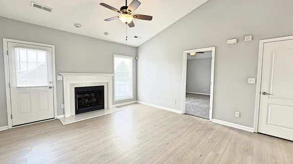 an empty room with wooden floor a ceiling fan and windows
