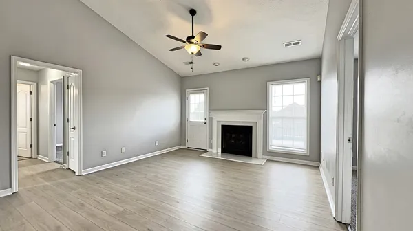 an empty room with wooden floor fireplace and windows