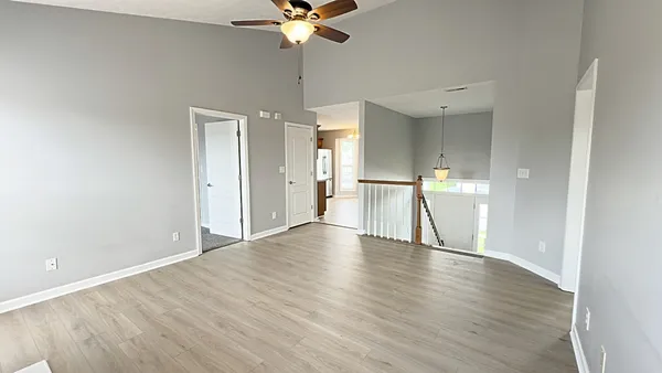 a view of an empty room with a chandelier fan