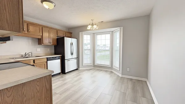 a kitchen with stainless steel appliances granite countertop a refrigerator a sink dishwasher a stove with wooden cabinets and floors