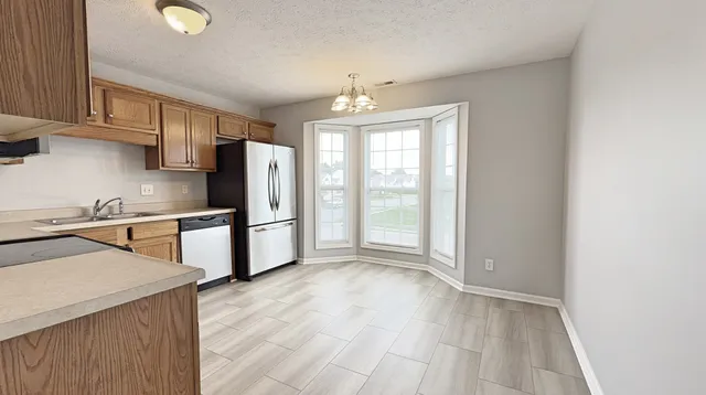 a kitchen with stainless steel appliances granite countertop a refrigerator a sink dishwasher a stove with wooden cabinets and floors