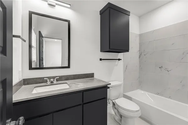 a bathroom with a granite countertop toilet sink and mirror