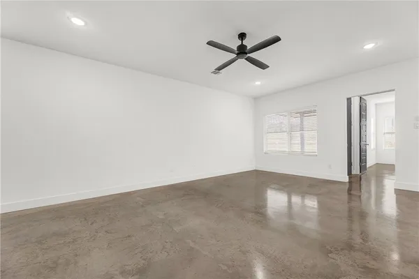 an empty room with windows and fan