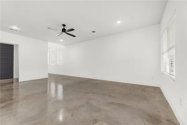 an empty room with windows and fan