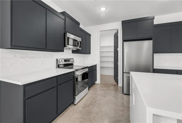 a kitchen with stainless steel appliances a refrigerator a sink and white cabinets