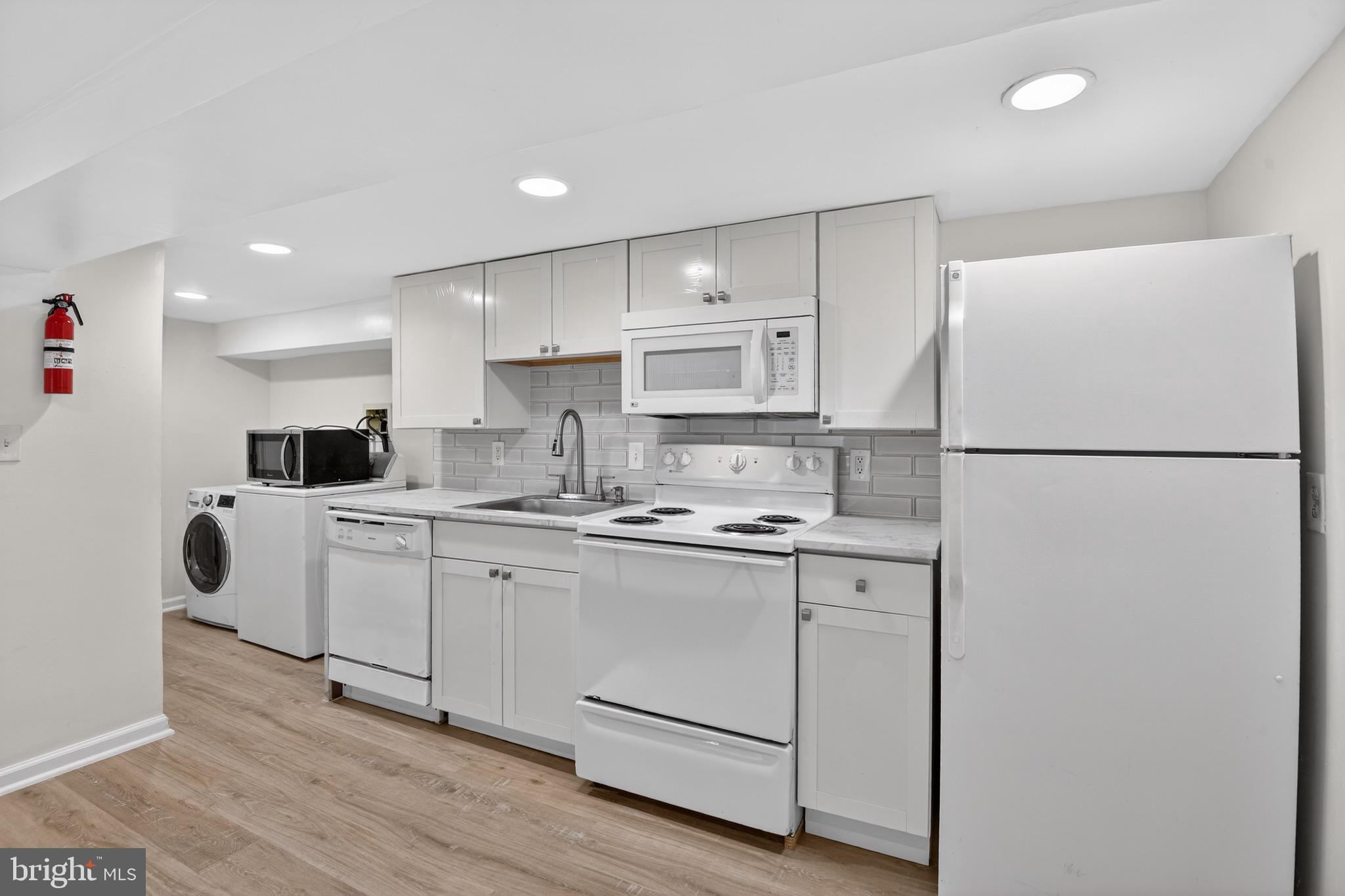 141 Uhland Terrace Northeast Washington, DC 20002 - Photo 6 of 16 a kitchen with white cabinets and white appliances