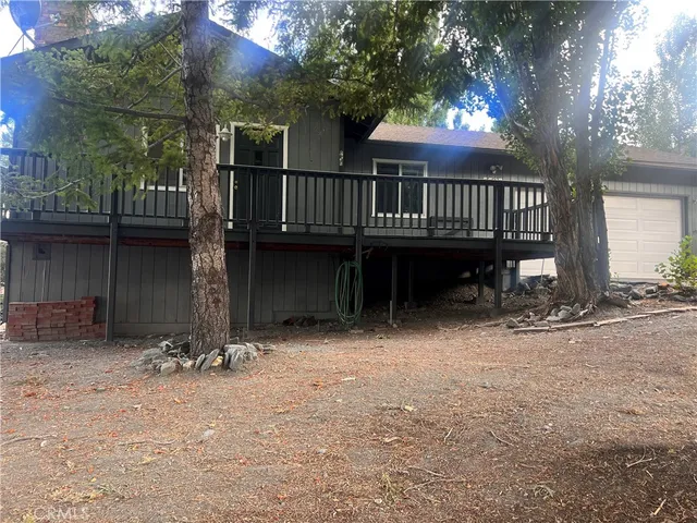 a view of a house with a wooden deck and a backyard