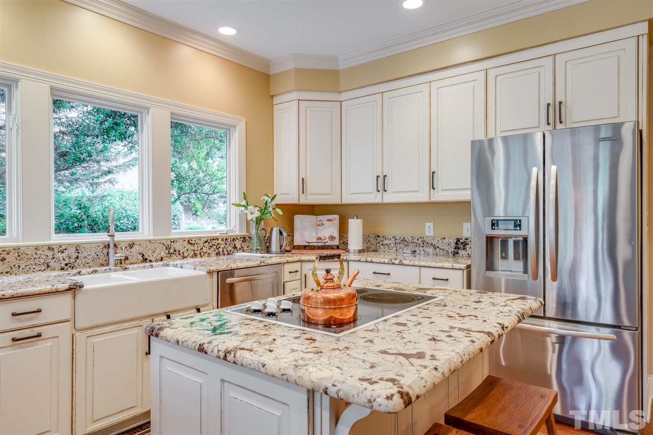 7604 Kelmscot Way Raleigh, NC 27615 - Photo 13 of 30 a kitchen with granite countertop a stove a sink a refrigerator and white cabinets