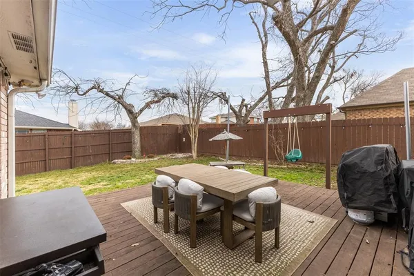 a view of a roof deck with table and chairs couches wooden floor and fence