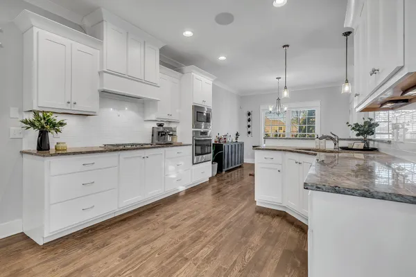 a large kitchen with stainless steel appliances kitchen island granite countertop a sink a stove and white cabinets