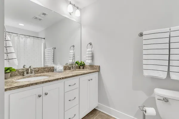 a bathroom with a granite countertop sink a toilet and a mirror