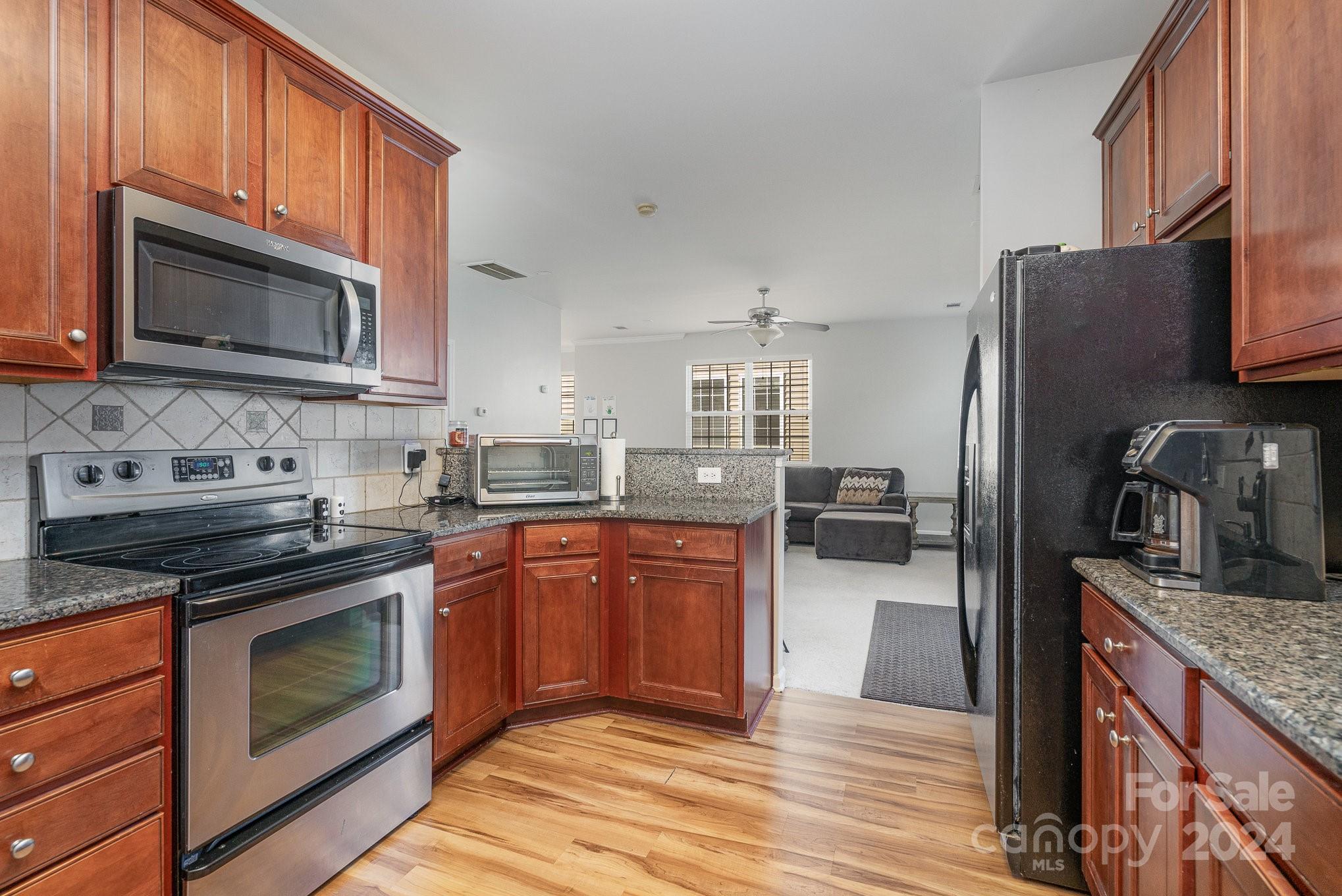 3367 Streamside Drive Davidson, NC 28036 - Photo 14 of 35 a kitchen with stainless steel appliances granite countertop a stove top oven microwave and refrigerator