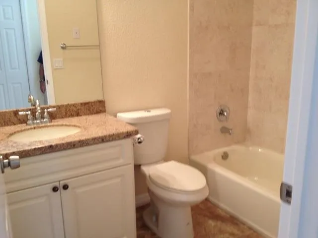 a bathroom with a granite countertop sink a toilet and bathtub