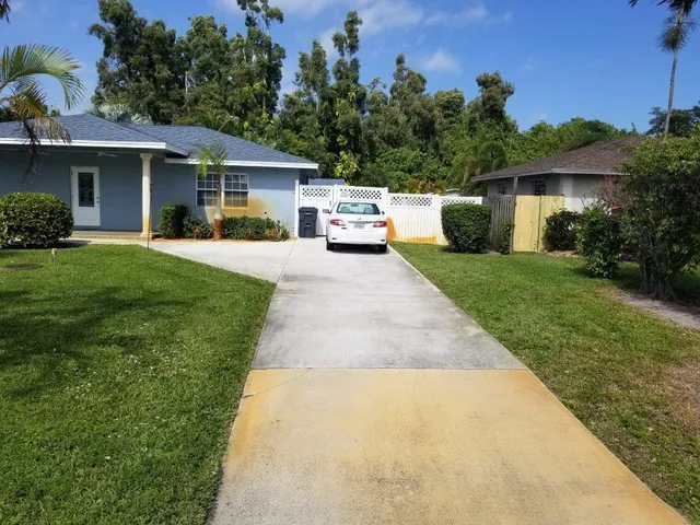 a front view of a house with a garden and trees