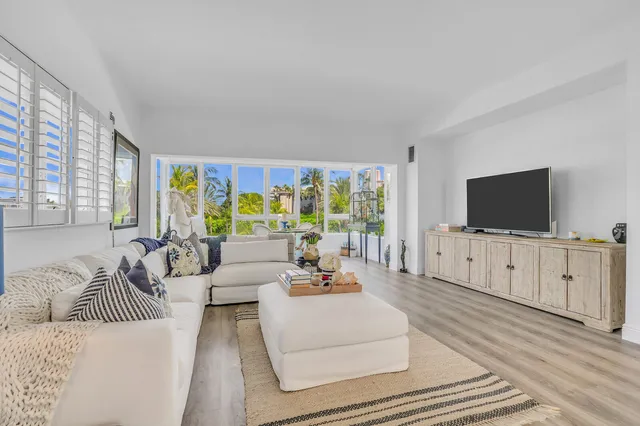 a living room with furniture a flat screen tv and a large window