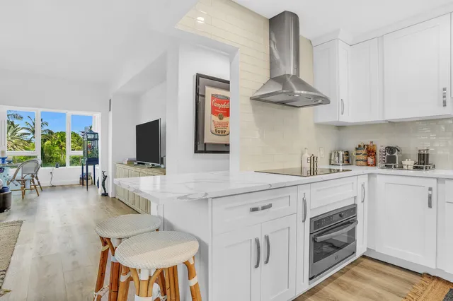 a kitchen with stainless steel appliances a stove a sink dishwasher and a flat screen tv