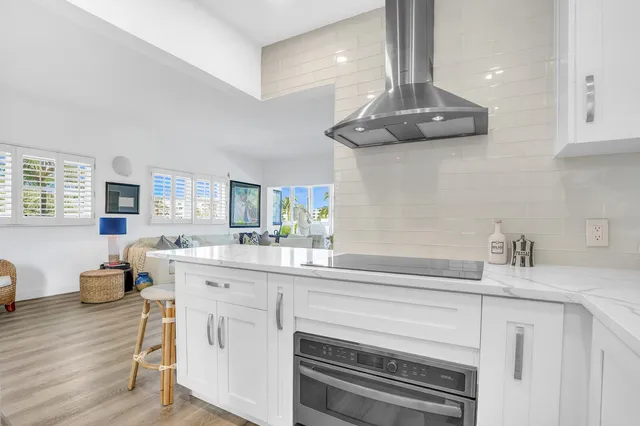 a kitchen with stainless steel appliances kitchen island granite countertop a stove and white cabinets with wooden floor