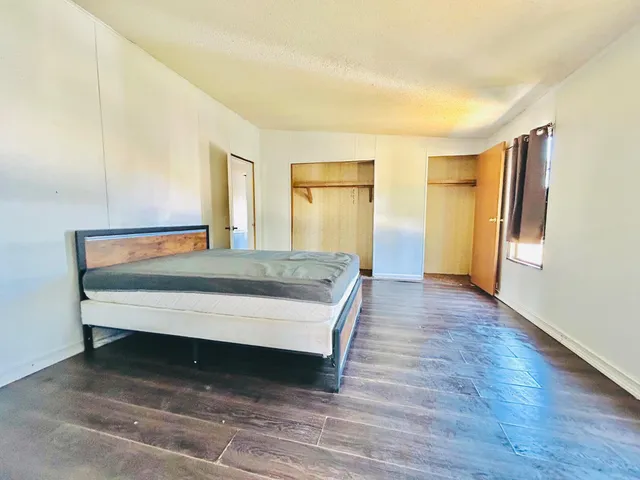 a spacious bedroom with a bed and wooden floor