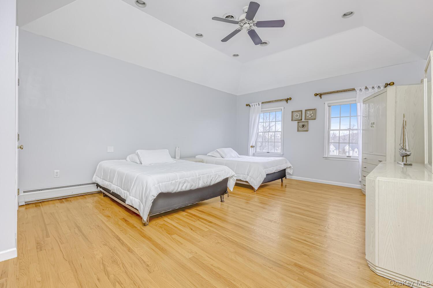 22 Golden Road Suffern, NY 10901 - Photo 28 of 41 Bedroom featuring a tray ceiling, light wood finished floors, a baseboard heating unit, and a ceiling fan