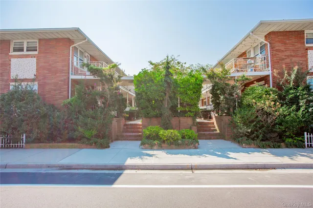 a view of a brick house with a yard and large tree