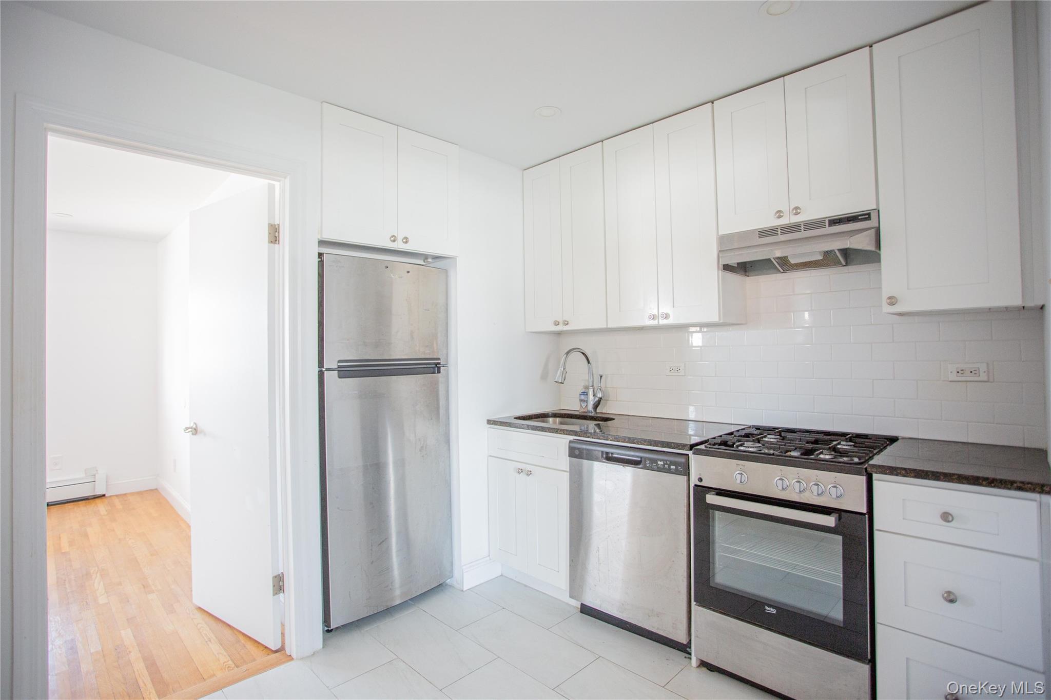 340 East Broadway, Unit 112 Long Beach, NY 11561 - Photo 8 of 19 a kitchen with white cabinets and stainless steel appliances