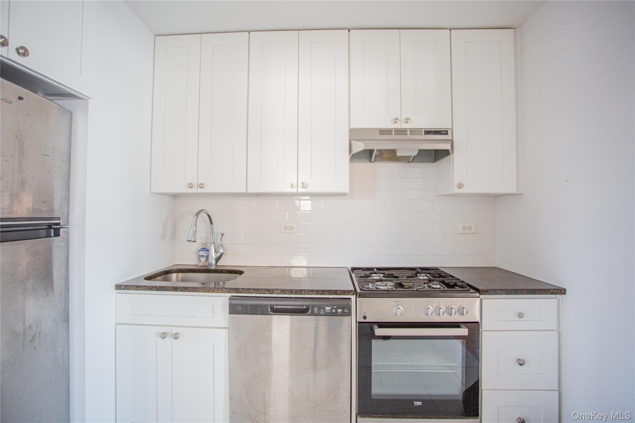 340 East Broadway, Unit 112 Long Beach, NY 11561 - Photo 9 of 19 a kitchen with stainless steel appliances granite countertop a sink stove and refrigerator