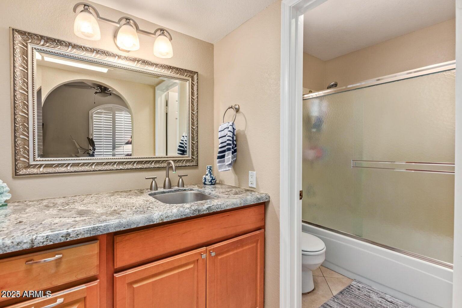 6945 East Cochise Road, Unit 130 Paradise Valley, AZ 85253 - Photo 18 of 24 a bathroom with a granite countertop sink mirror vanity and toilet