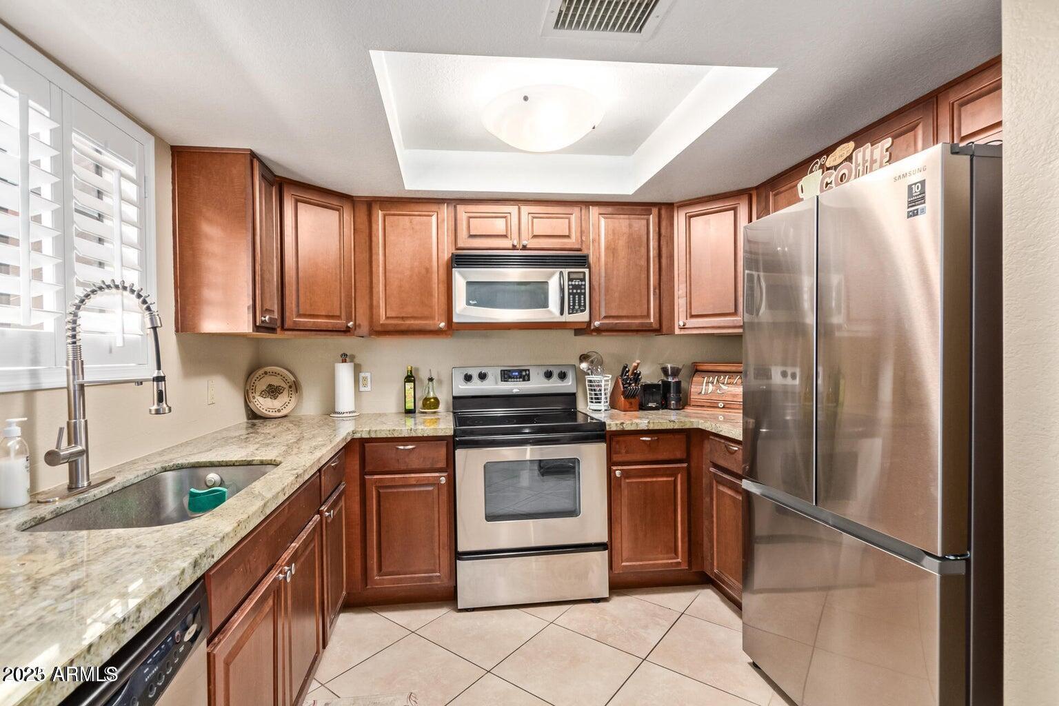 6945 East Cochise Road, Unit 130 Paradise Valley, AZ 85253 - Photo 9 of 24 a kitchen with stainless steel appliances granite countertop a stove a sink dishwasher a refrigerator and a microwave