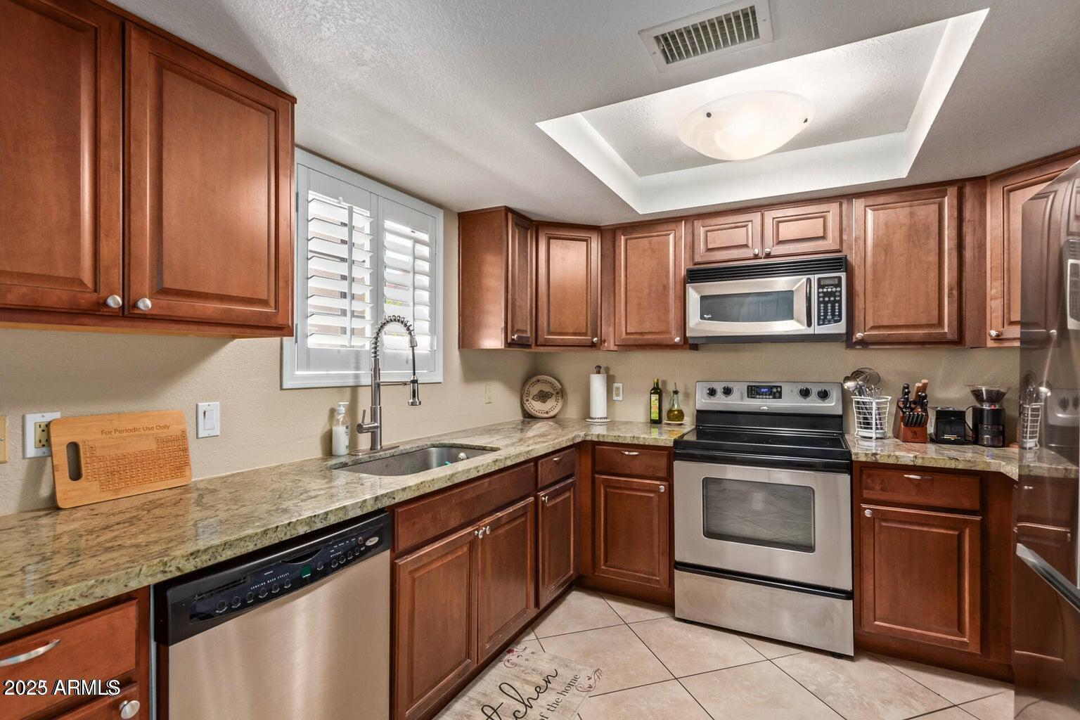 6945 East Cochise Road, Unit 130 Paradise Valley, AZ 85253 - Photo 10 of 24 a kitchen with granite countertop a sink stainless steel appliances and cabinets
