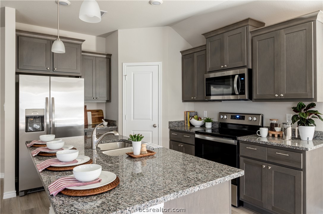 2159 Chief Street Bryan, TX 77807 - Photo 6 of 22 a kitchen with stainless steel appliances granite countertop a sink a stove a microwave a dining table and chairs with wooden floor