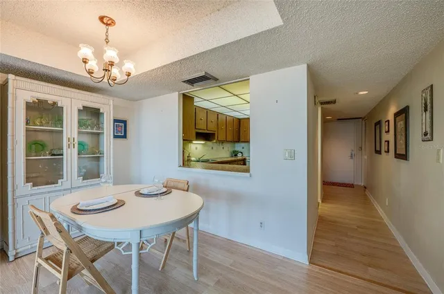 a dining room with wooden floor a chandelier a wooden table and chairs