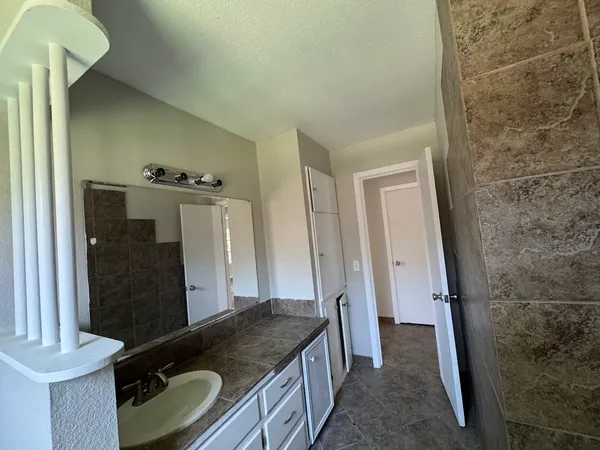 a bathroom with a granite countertop sink a mirror and shower