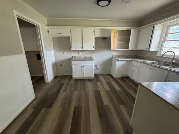 a large kitchen with a sink a stove a refrigerator and white cabinets