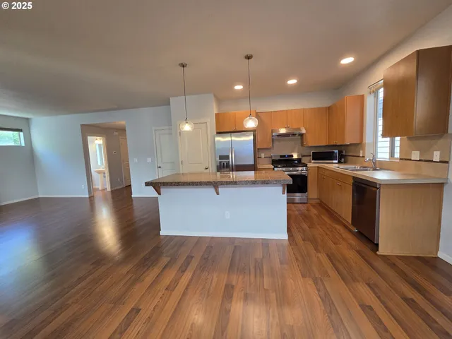 a kitchen with stainless steel appliances granite countertop a refrigerator a sink a stove a microwave and wooden floor