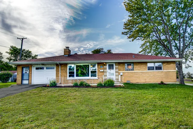 a front view of a house with a yard and trees