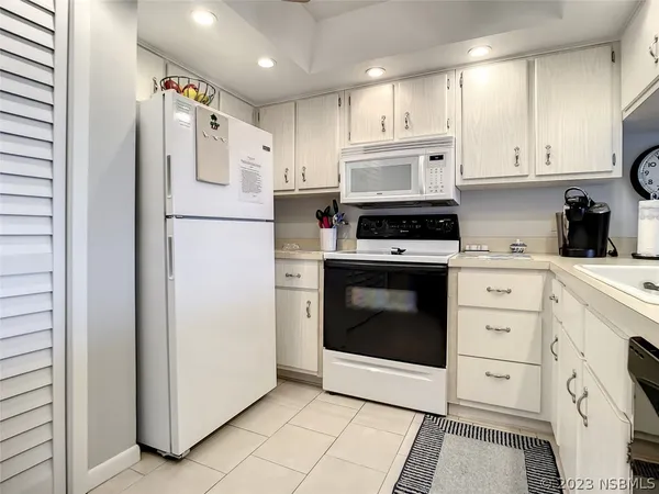 a kitchen with white cabinets and white appliances