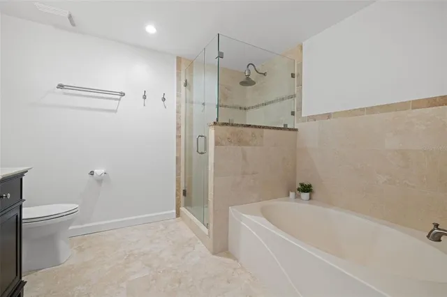 a bathroom with a tub shower sink vanity and a toilet