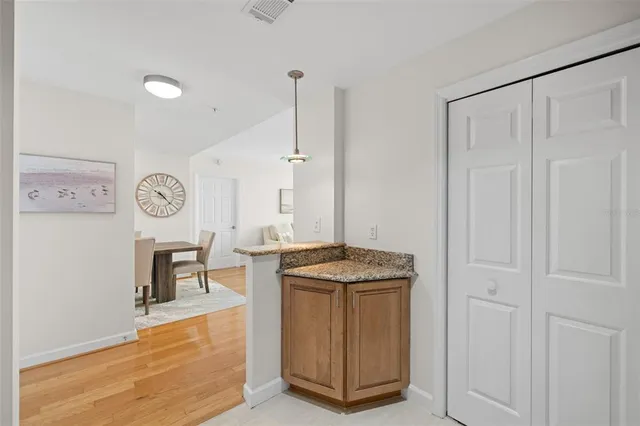 a hall with a stove a sink dishwasher and a dining table with wooden floor