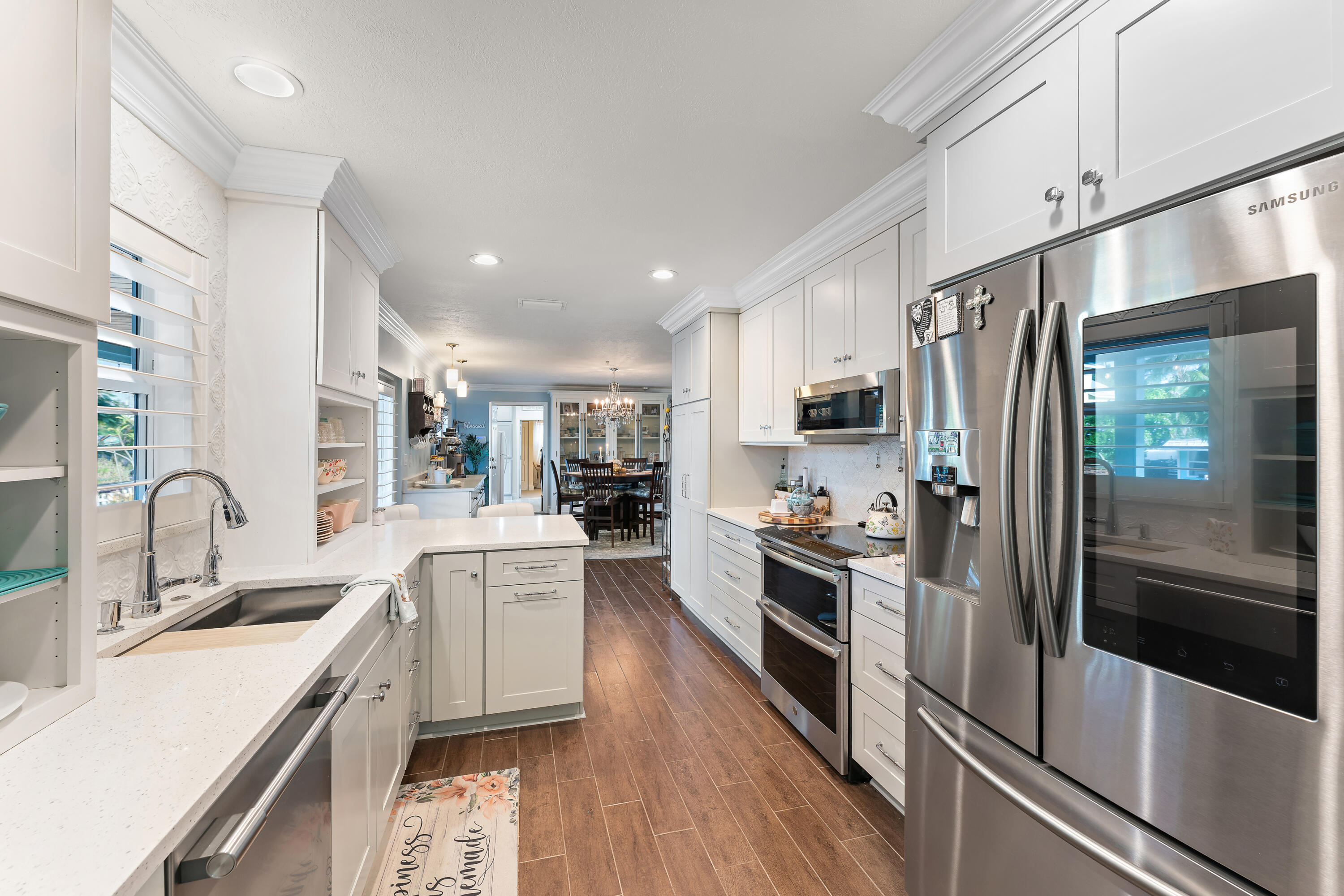 581 Southwest Timber Trail Stuart, FL 34997 - Photo 26 of 45 a kitchen with stainless steel appliances granite countertop a refrigerator a stove top oven a sink dishwasher and white cabinets with wooden floor